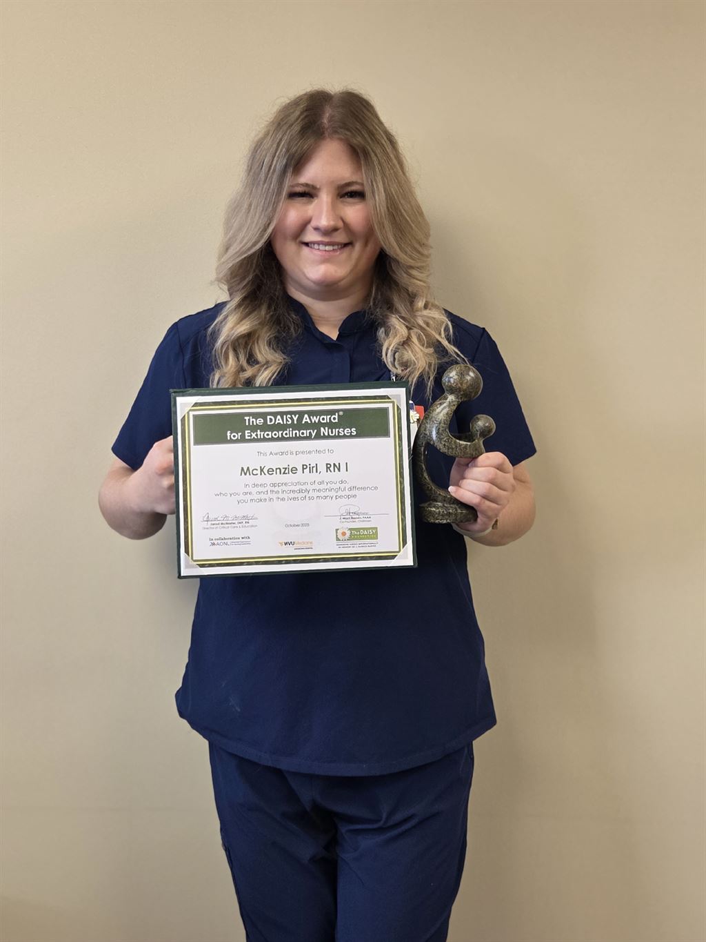 Photo of McKenzie Pirl, R.N. holding DAISY Award certificate and trophy.