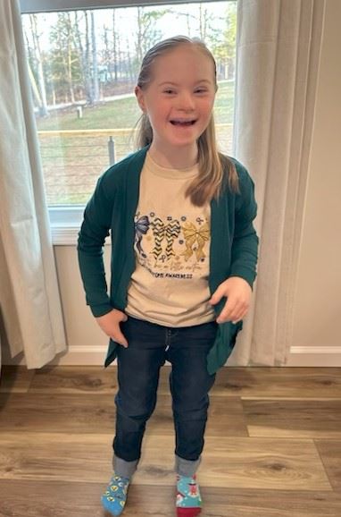 A young girl poses for a photo wearing mismatched socks for World Down Syndrome Day awareness