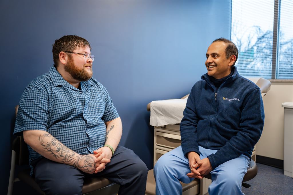 Timony Walter sits and talks with Dr. Vishal Gupta in an exam room.