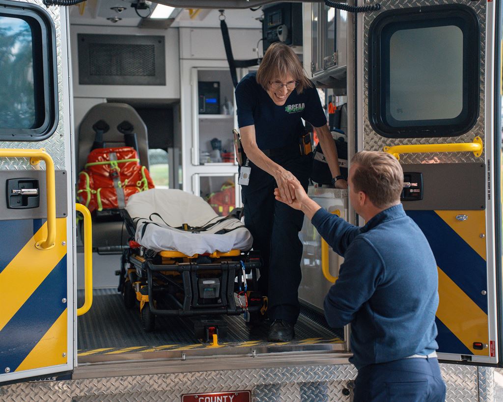 An EMS employee in an ambulance shakes hands with Mark O'Hern, Regional President of WVU Hospitals East and President and CEO of WVU Medicine Berkeley Medical Center