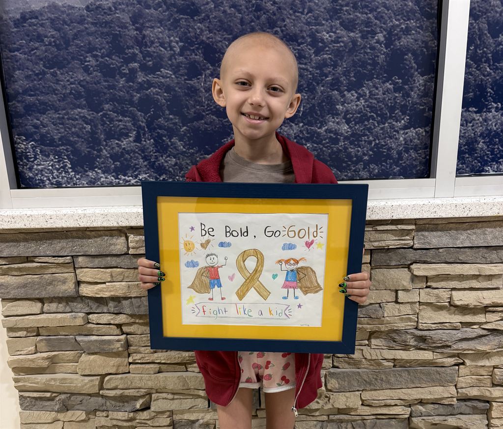Pediatric Cancer Patient Layla Dempsey poses for a photo with her drawing.