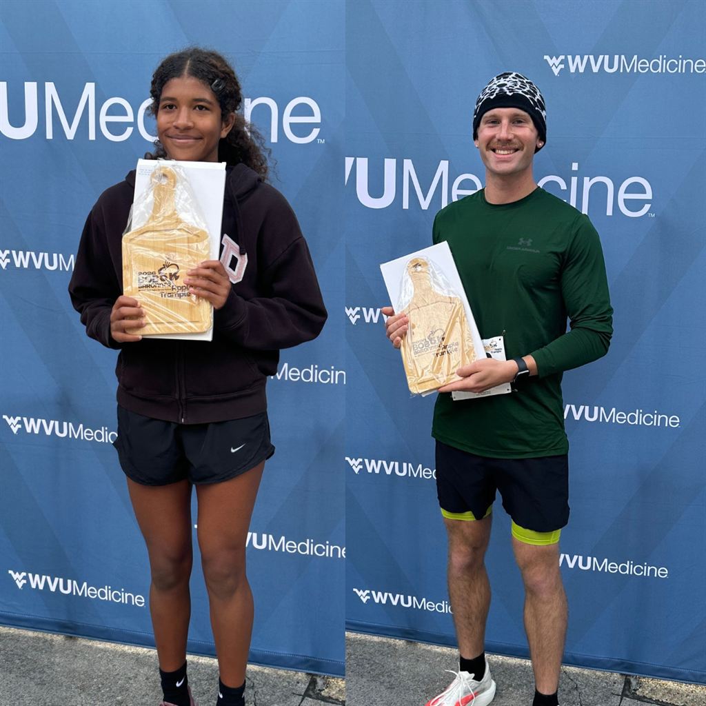 2026 Bob Baronner Apple Trample 5K Top Racers Amie Rivas, Aidan Kuriger pose with their winnings against a backdrop with the WVU Medicine logo.