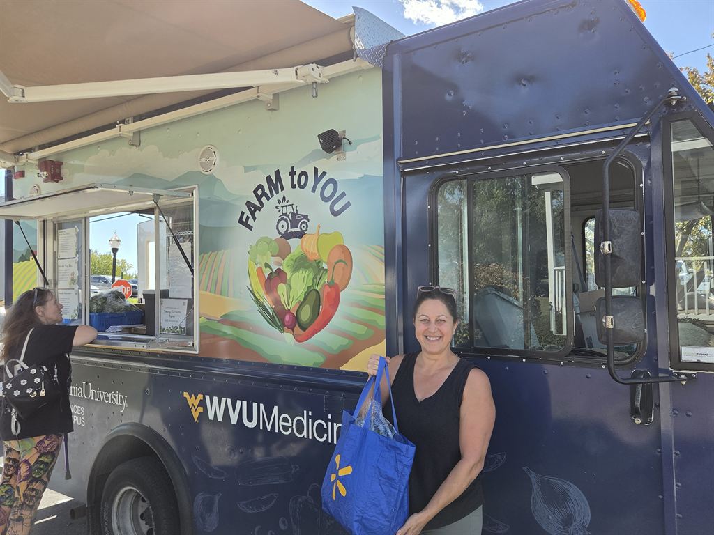 A patient poses next to the Farm to You truck after picking up their produce