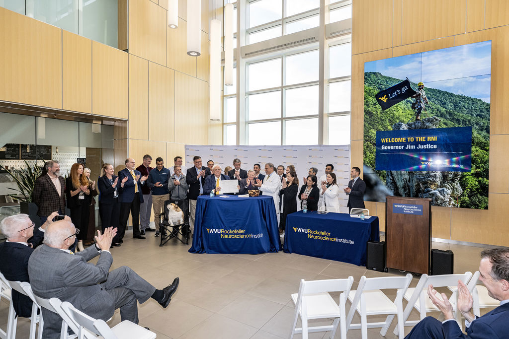 Gov. Jim Justice (center) was joined by WVU President Gordon Gee, Dr. Ali Rezai, state lawmakers, and researchers and staff members with the WVU Rockefeller Neuroscience Institute as he ceremonially signed legislation Monday (Oct. 28) providing $2 million in supplemental funding to support first-in-the-world clinical research studies at RNI using focused ultrasound neuromodulation to treat food addiction, post-traumatic stress disorder and other conditions. (WVU Photo/Brian Persinger)