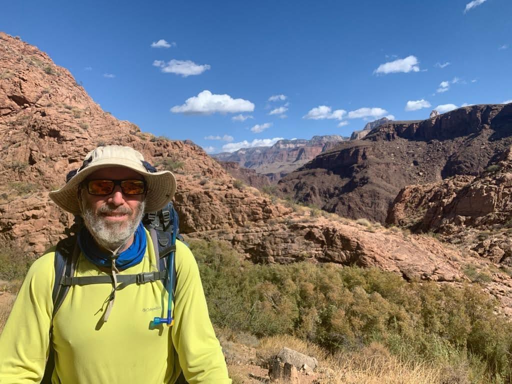 man-in-hat-and-sunglasses-hiking-in-a-canyon